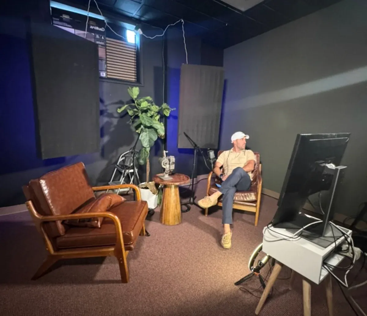 The AV-Ator Studios recording room: acoustic panels, leather seating, a boom microphone, and a monitor on a stand.
